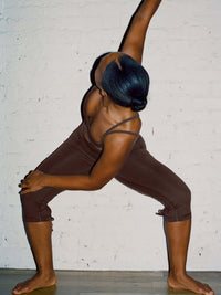 Model stretching in Puddle Capri, showing keyhole cut-out with adjustable ties and a wide waistband.