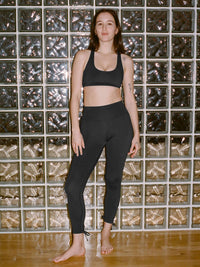 Model standing in Puddle Legging in Black with adjustable ties at the back of the leg, styled for activewear.
