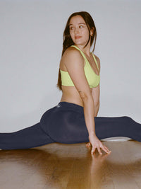 Model in a split wearing Puddle Legging in Navy, featuring a wide waistband and keyhole cut out.