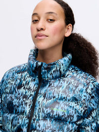 Model wearing Rainy Floral Puff in blue, with the puffer's glossy fabric and high collar design.