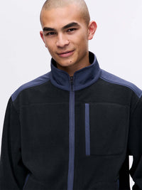 Model wearing RecFleece Relaxed Full Zip in Black with contrast RecTrek shoulder panels and a chest pocket.