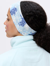 Rear view of woman wearing RecFleece Snap Jacket in light blue, with coordinating floral headband.