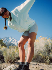 Model stretching in RecFleece Snap Jacket in Light Blue, featuring a snap front and dolman sleeve for a relaxed fit.