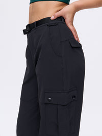 Side view of model wearing RecTrek Cargo Pant in Black with adjustable belted waistband and utility pockets.