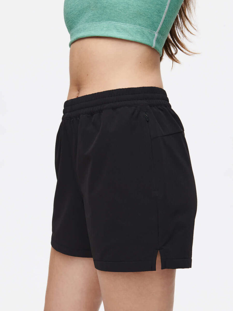 Side view of model wearing RecTrek 4" Short in Black, featuring a zippered pocket and relaxed fit.