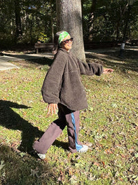 Model walking outside in Candy Fleece Snap Jacket in Brown, with the oversized fit and warm texture.