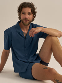 Model sitting in SolarCool Camp Collar in Deep Ocean, lightweight and breathable fabric for activities.