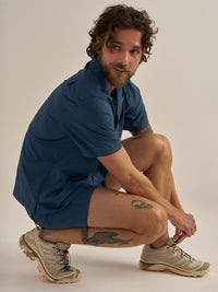 Model crouching in SolarCool Camp Collar in Navy, featuring a lightweight breathable fabric for outdoor activities.