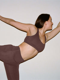 Model in a yoga pose wearing Star Bra in dark plum, featuring wide shoulder straps for support.