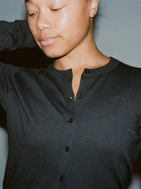 Model in black Sugar Cardigan, featuring soft cotton cashmere and hand-embroidered OV signature.