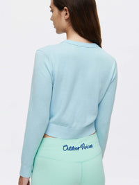 Back view of Sugar Cardigan in Light Blue, soft cotton cashmere with hand-embroidered signature.