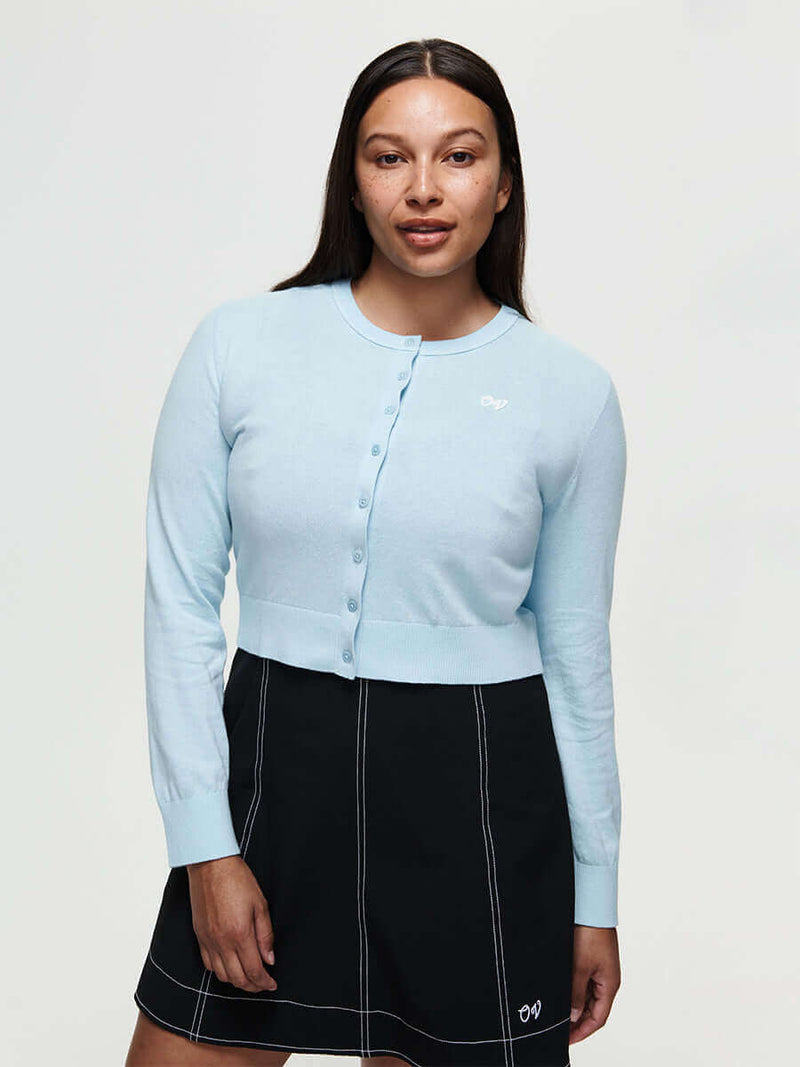 Model wearing Sugar Cardigan in Light Blue, lightweight knit cotton cashmere with hand-embroidered signature.