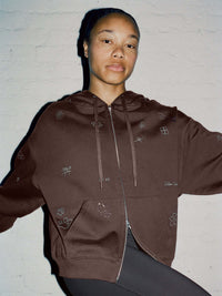 Model wearing Sunny Hoodie in Brown, relaxed fit with playful embroidered designs and 2-way zipper.