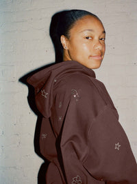 Model wearing Sunny Hoodie in Dark Brown, with embroidered star details and a relaxed fit for everyday style.