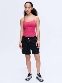 Model wearing TechSweat Move Free Tank in Pink with adjustable straps, paired with black shorts for activewear.