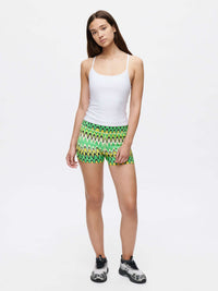 Model wearing TechSweat Move Free Tank in White, showing adjustable racerback straps paired with vibrant patterned shorts.