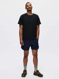 Model standing in ThinkFast Mesh Shortsleeve in Black, paired with navy shorts, showing a classic fit for activewear.