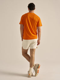 Model in back view wearing ThinkFast Mesh Shortsleeve in Bright Orange, designed for breathability and comfort.