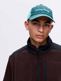 Model wearing Trucker Hat in Teal, featuring the 'Doing Things' embroidered logo.