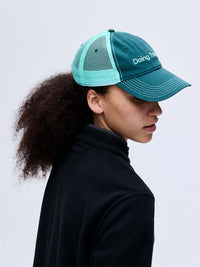 Side view of model wearing Trucker Hat in Teal, with breathable mesh and a classic curved brim.