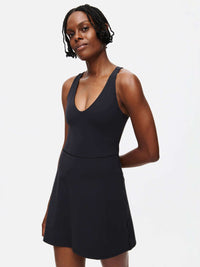 Model wearing Volley Dress in Black with V-neck design and fit-and-flare silhouette, styled for activewear.