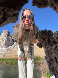 Model leaning forward wearing Waffle Longsleeve in Olive with a relaxed fit, styled for outdoor adventures.