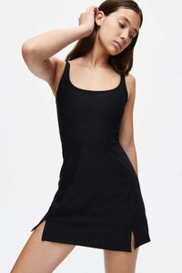 Model posing in Warmup Dress in Black, featuring side slits for enhanced mobility and style.