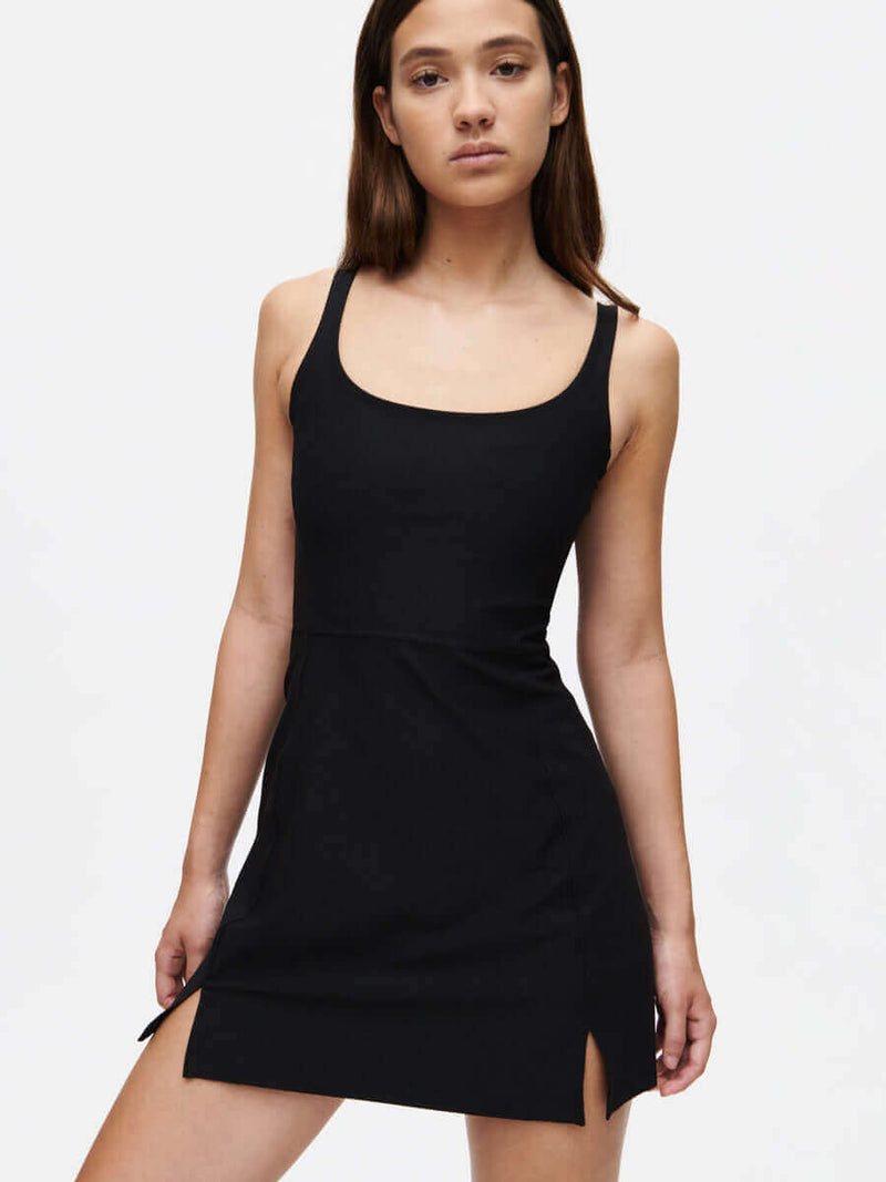 Model posing in Warmup Dress in Black, featuring side slits for added mobility.