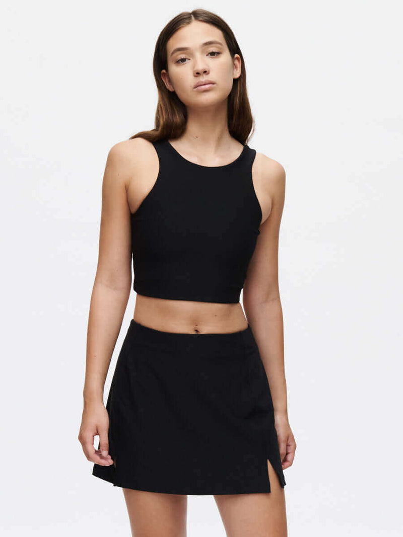 Model posing in Warmup 2.5" Skort in Black, featuring a split detail for enhanced movement.