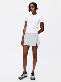 Model standing in Warmup 2.5" Skort in Gray, featuring a side slit for ease of movement.