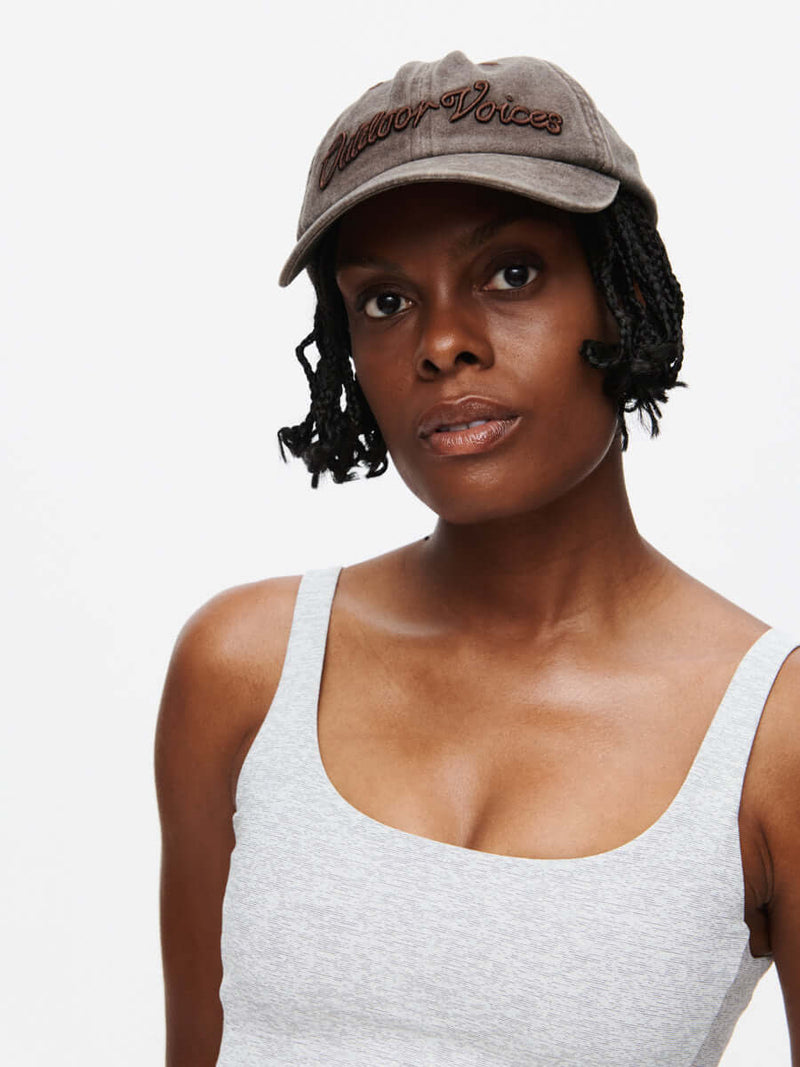 Model wearing Washed Hat in Brown, featuring raised Outdoor Voices signature.