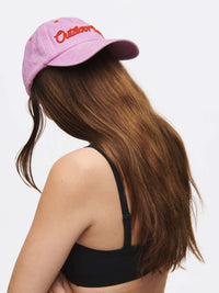 Model wearing Washed Hat in Light Purple with raised Outdoor Voices lettering, styled with a black sports bra.