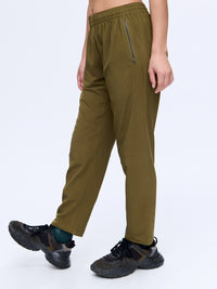 Model standing in Zephyr 26" Pant in Olive, featuring zippered pockets and adjustable drawstring waist.