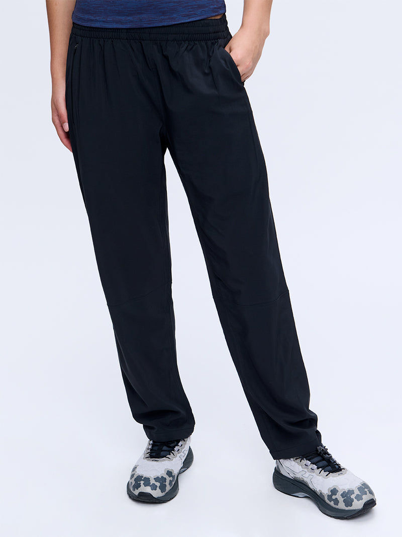 Model posing in Zephyr 26" Pant in Black, featuring zippered pockets and a drawstring waist.