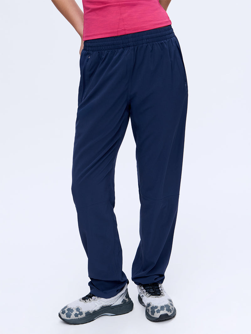 Model in pink top wearing Zephyr 29" Pant in Navy, featuring a custom-fit drawstring waist.